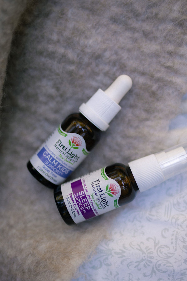 Calm Kids Support oral drops and Sleep Support oral spray lying on a soft grey blanket