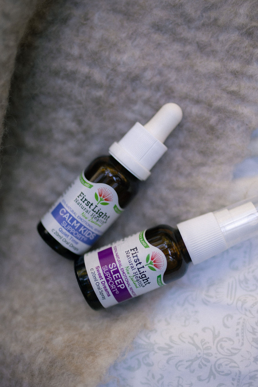 Calm Kids Support oral drops and Sleep Support oral spray lying on a soft grey blanket